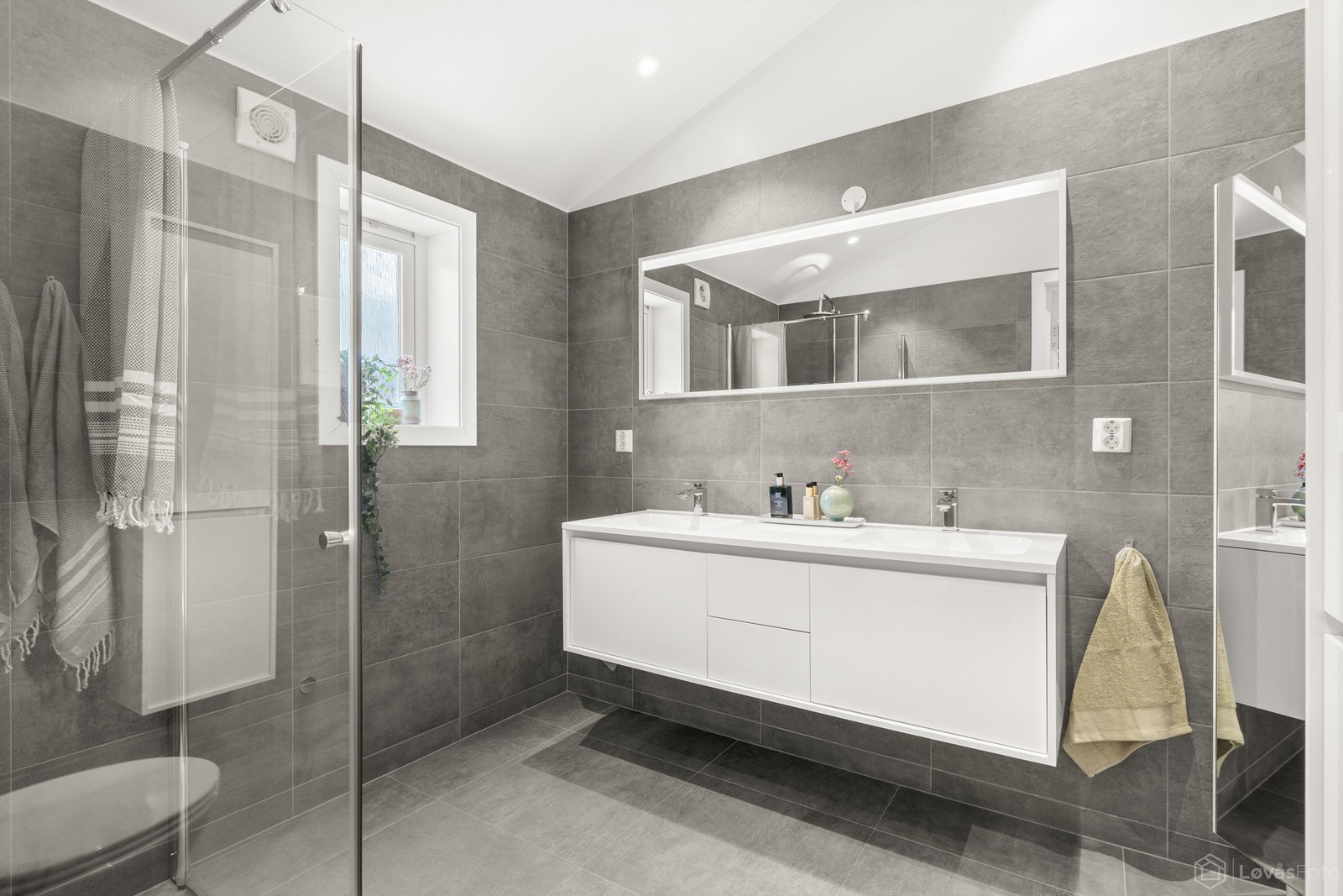 Moderne en-suite bad fra 2016 med heldekkende dobbelservant og flislagte overflater. Galleribilde