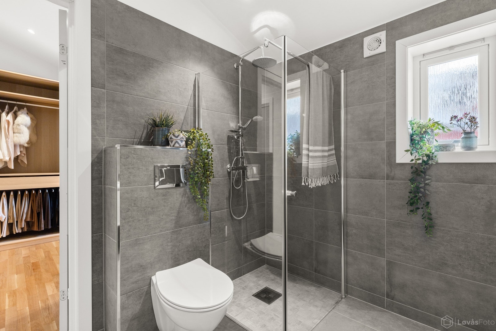 Badet er utstyrt med dusjhjørne med glassvegger, regnfalldusj og vegghengt toalett. Galleribilde