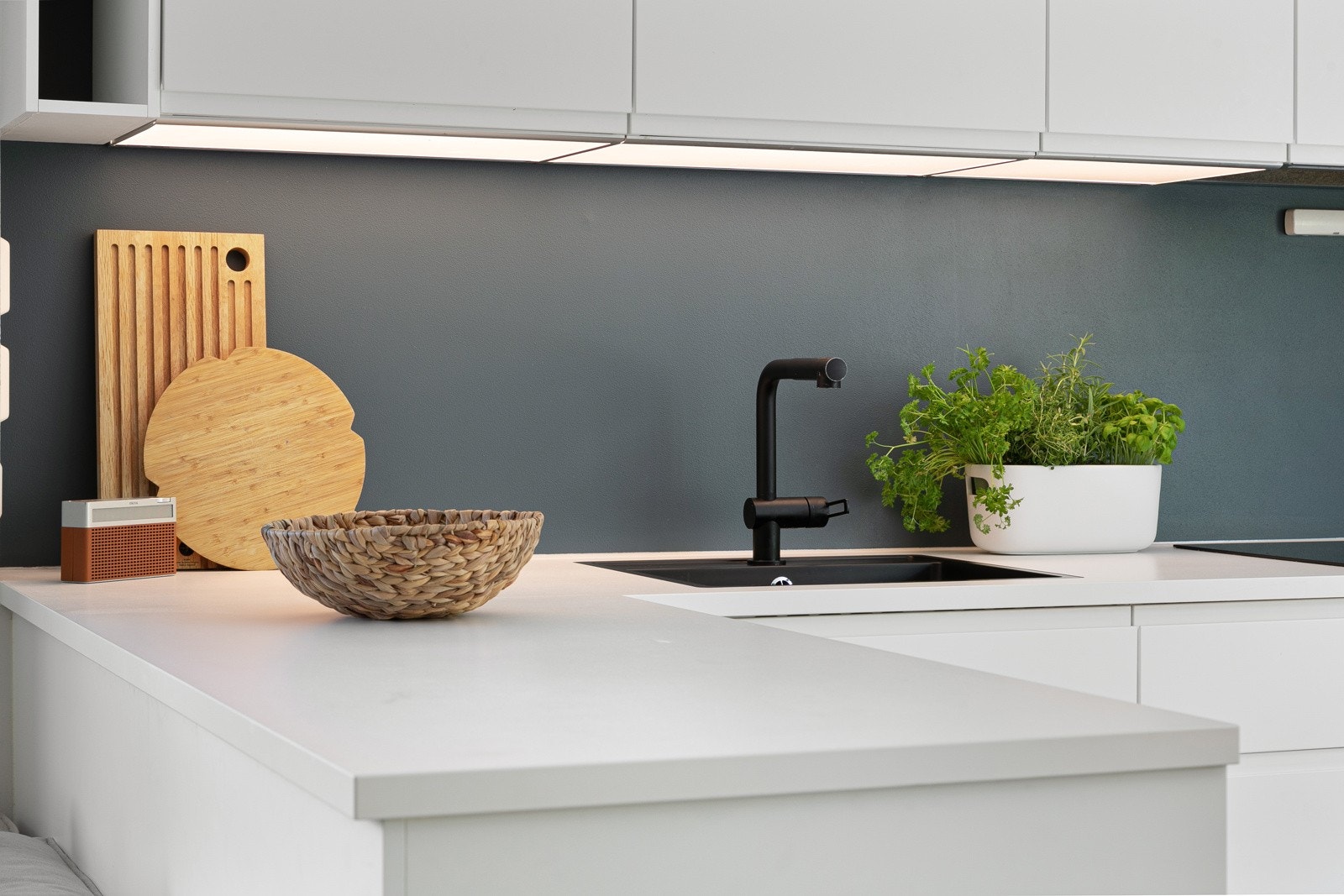 Hvit laminat benkeplate med planlimt vask og ett-greps armatur i sort med uttrekkbar tut. Galleribilde