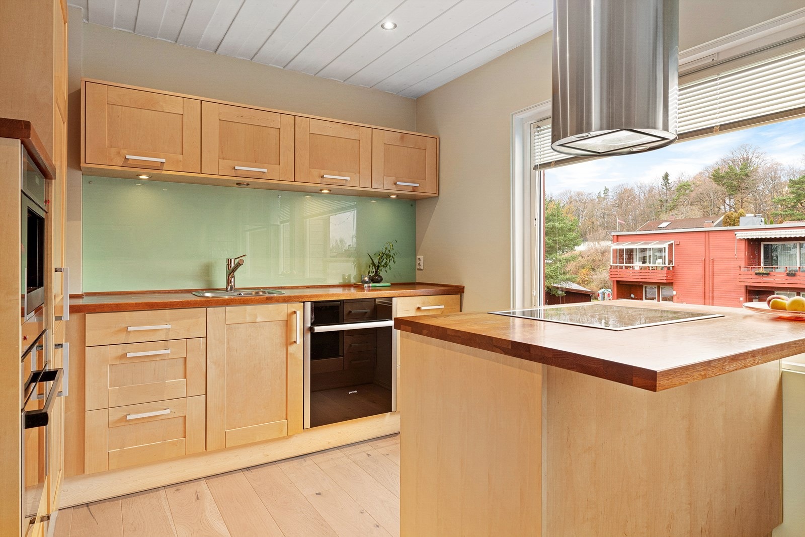 Pent og innholdsrikt kjøkken fra 2010 med integrerte hvitevarer og kjøkkenøy med takmontert ventilator. Galleribilde