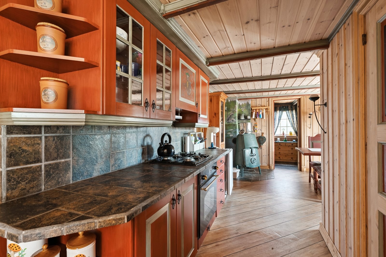 Malt profilert kjøkkeninnredning med gass koketopp og stekeovn samt frittstående kjøleskap. Galleribilde