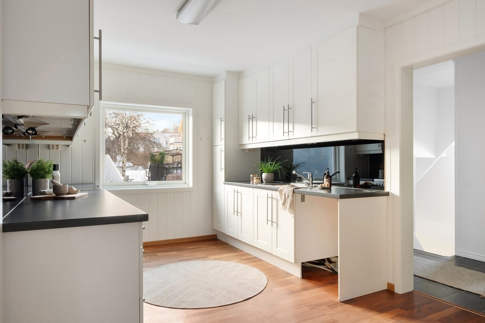 Skapinnredning med fronter i malt MDF og laminat benkeplate. Hvitevarer består av komfyr og det er røropplegg for oppvaskmaskin. Galleribilde