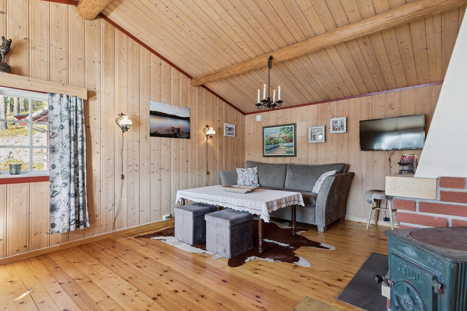 Stuen er et lunt samlingspunkt med vegger og himling i trepanel og lakkert tregulv. Galleribilde