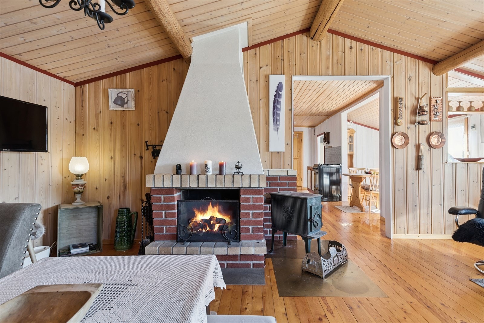 Den teglsteinsmurte peisen og en eldre vedovn sørger for varme og en klassisk hyttestemning. Galleribilde