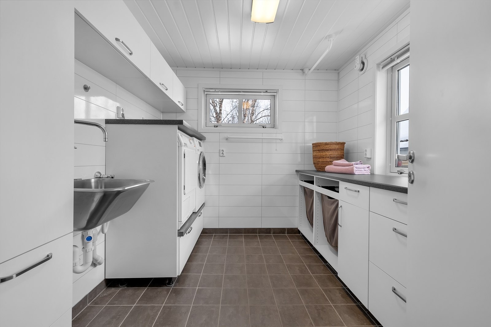 Funksjonelt vaskerom i tilknytning til hovedbad med praktisk arbeidsbenk og gode oppbevaringsløsninger Galleribilde