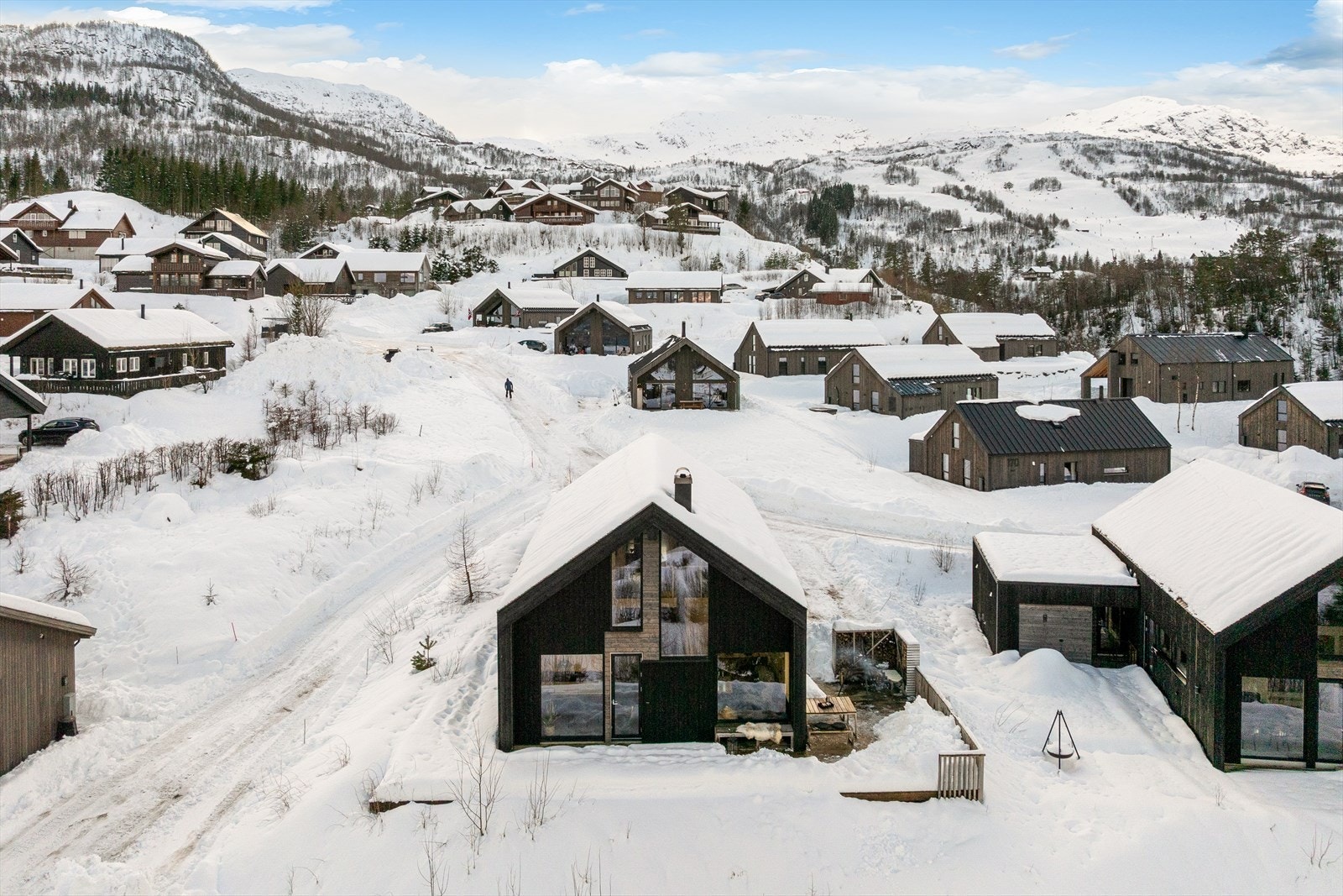 Moderne fritidsbolig med karakteristisk arkitektur og store vindusflater som slipper naturen inn. Boligen fremstår helhetlig og solid med mørk trekledning som harmonerer med omgivelsene. Galleribilde