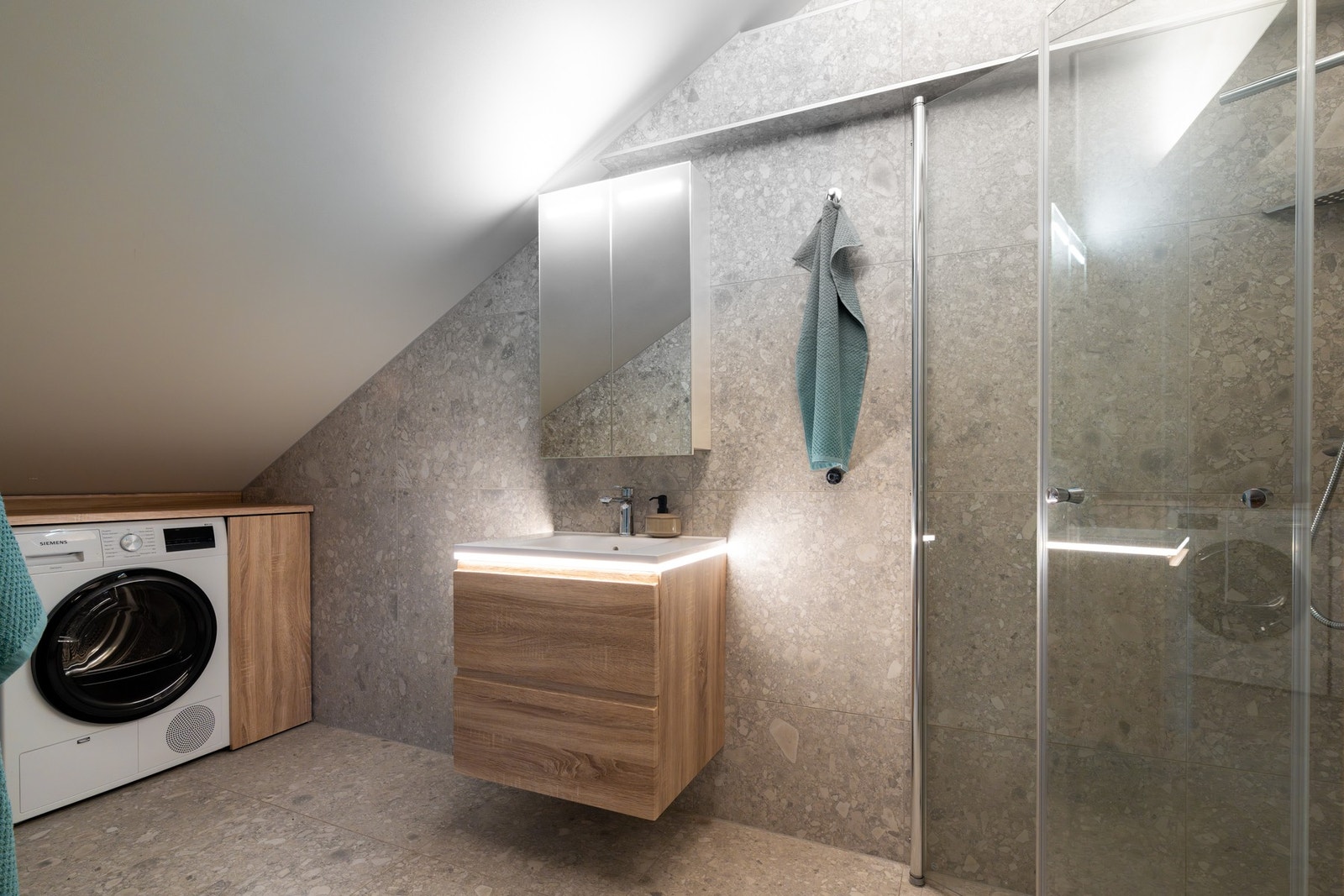 Baderommet er lekkert flislagt med varme i gulv. Innredningen består av servant på underskuffer, speilskap med belysning og vegghengt toalett. Galleribilde