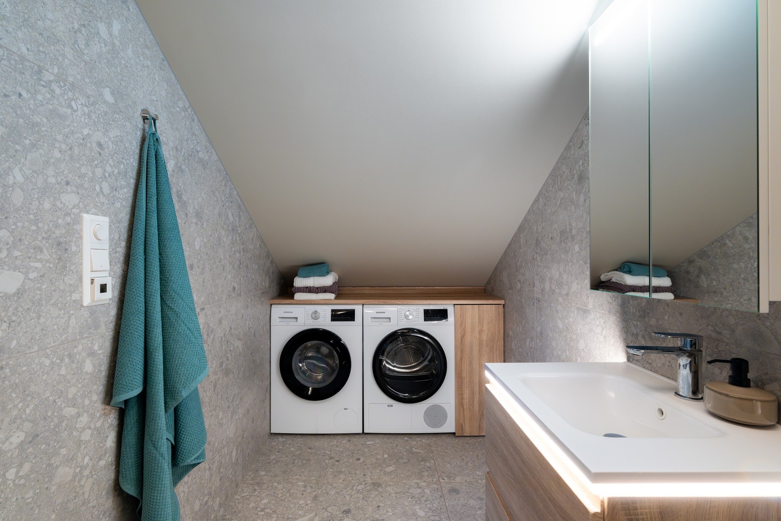 Innerst i rommet er det en praktisk nisje for vaskemaskin og tørketrommel. God arbeidsbenk for bretting av tøy, i tillegg til skap for vaskepulver og annet. Både vaskemaskin og tørketrommel blir stående. Galleribilde