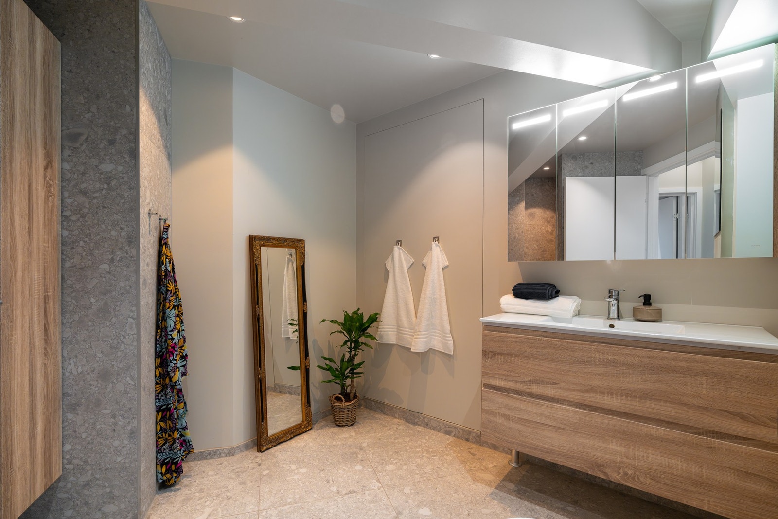 Bad 1 er plassert ved oppholdsrommet og er innredet med servant på underskuffer, speilskap med belysning, høyskap og vegghengt toalett. Galleribilde