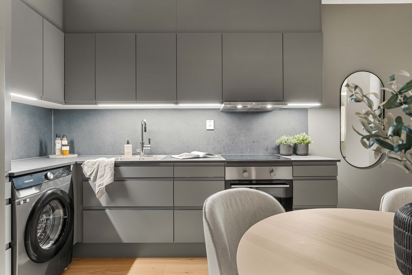 Kjøkkenet har moderne detaljer og integrert vaskemaskin for en plassbesparende løsning. Belysning under overskapene gir et eksklusivt preg. Galleribilde