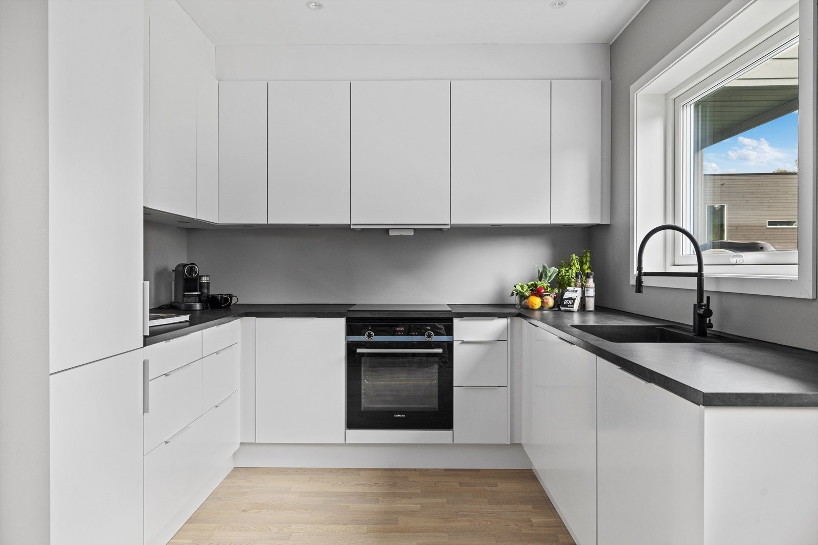 Tidsriktig innredning fra 2023 med hvite, slette fronter og benkeplate i laminat. Galleribilde