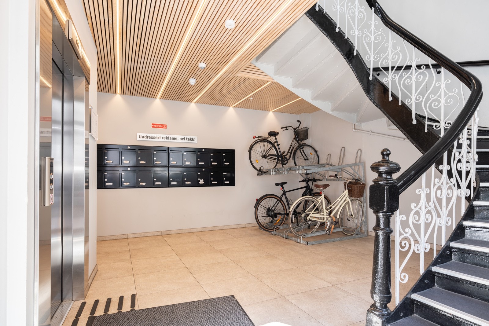 Moderne inngangsparti med flislagt gulv, postkasser og sykkelparkering. Galleribilde