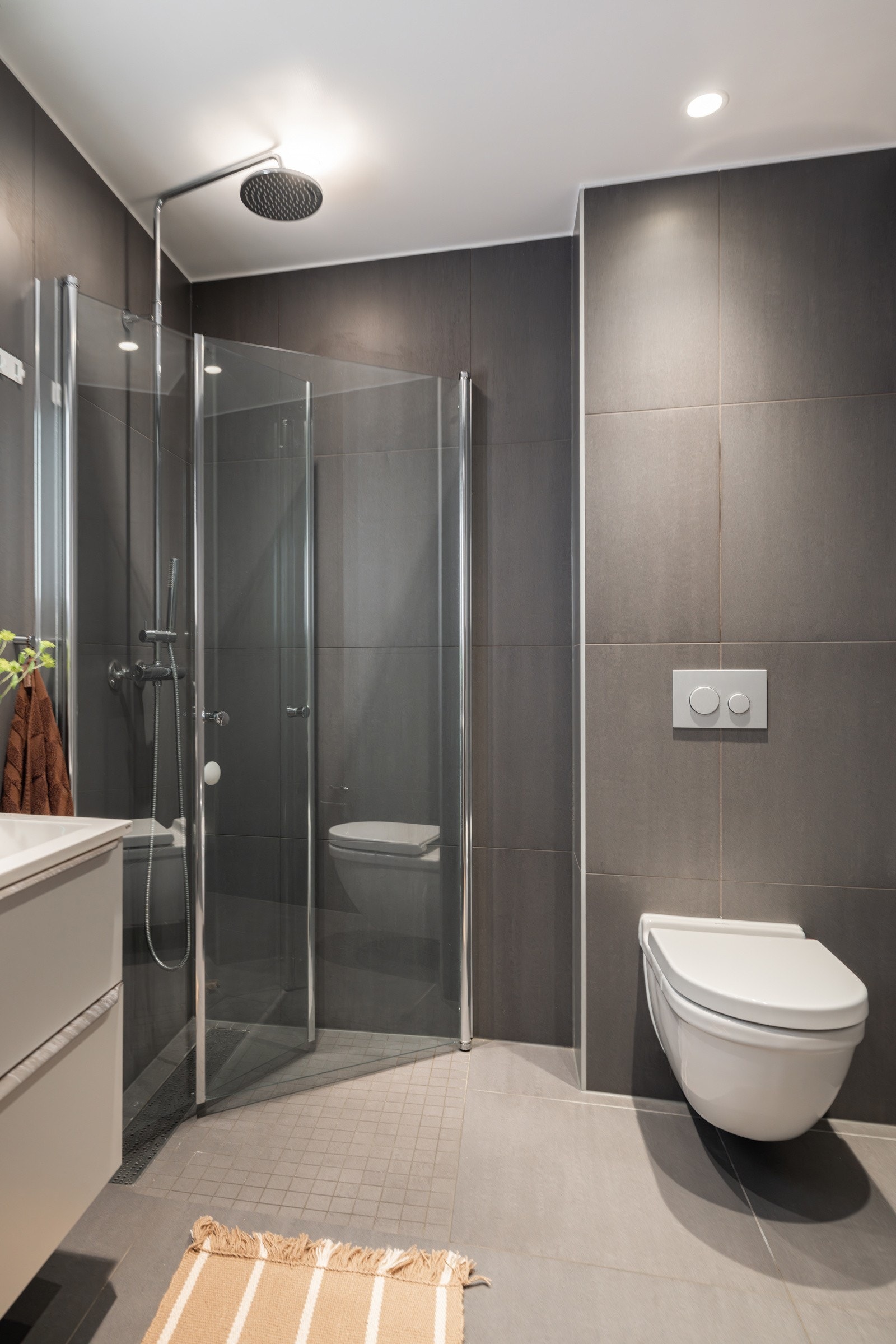 Baderommet er også utstyrt med dusjhjørne med innfellbare glassdører og både hånd- og regnfallsdusj, vegghengt toalett og opplegg for vaskemaskin. Galleribilde