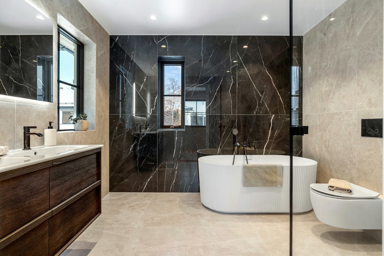 Bad tilknyttet hovedsoverommet er utstyrt med stilren servant med romslig baderomsinnredning, stort speil med integrert belysning samt moderne armaturer. Galleribilde