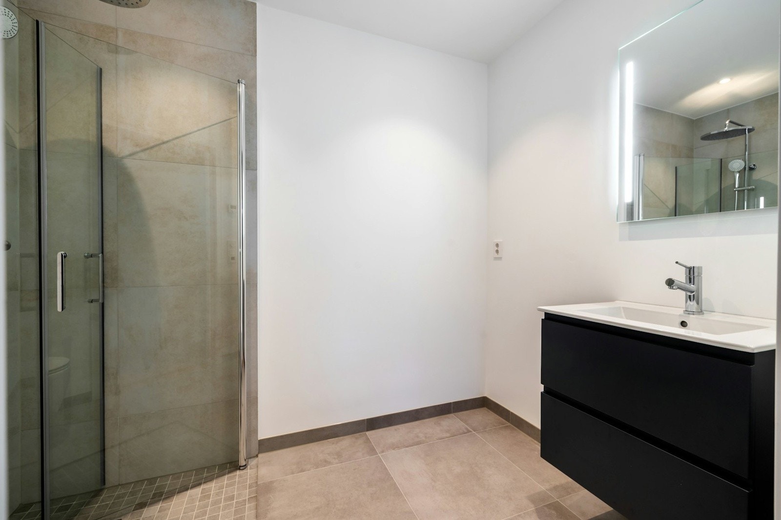 Bad i underetasjen er innredet med vegghengt toalett, servant med praktisk oppbevaringsløsning og speil med integrert belysning. Videre byr badet på et dusjhjørne med innfellbare glassvegger. Her er det også opplegg for vaskemaskin. Galleribilde