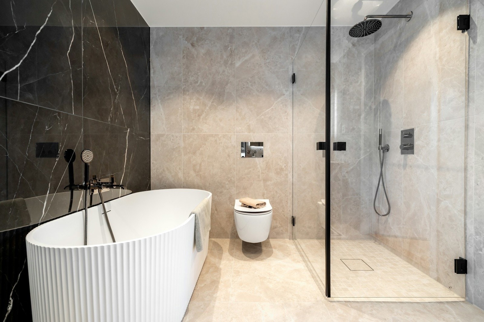 Rommet byr på et eksklusivt frittstående badekar og et dusjhjørne med innfellbare glassvegger. Galleribilde