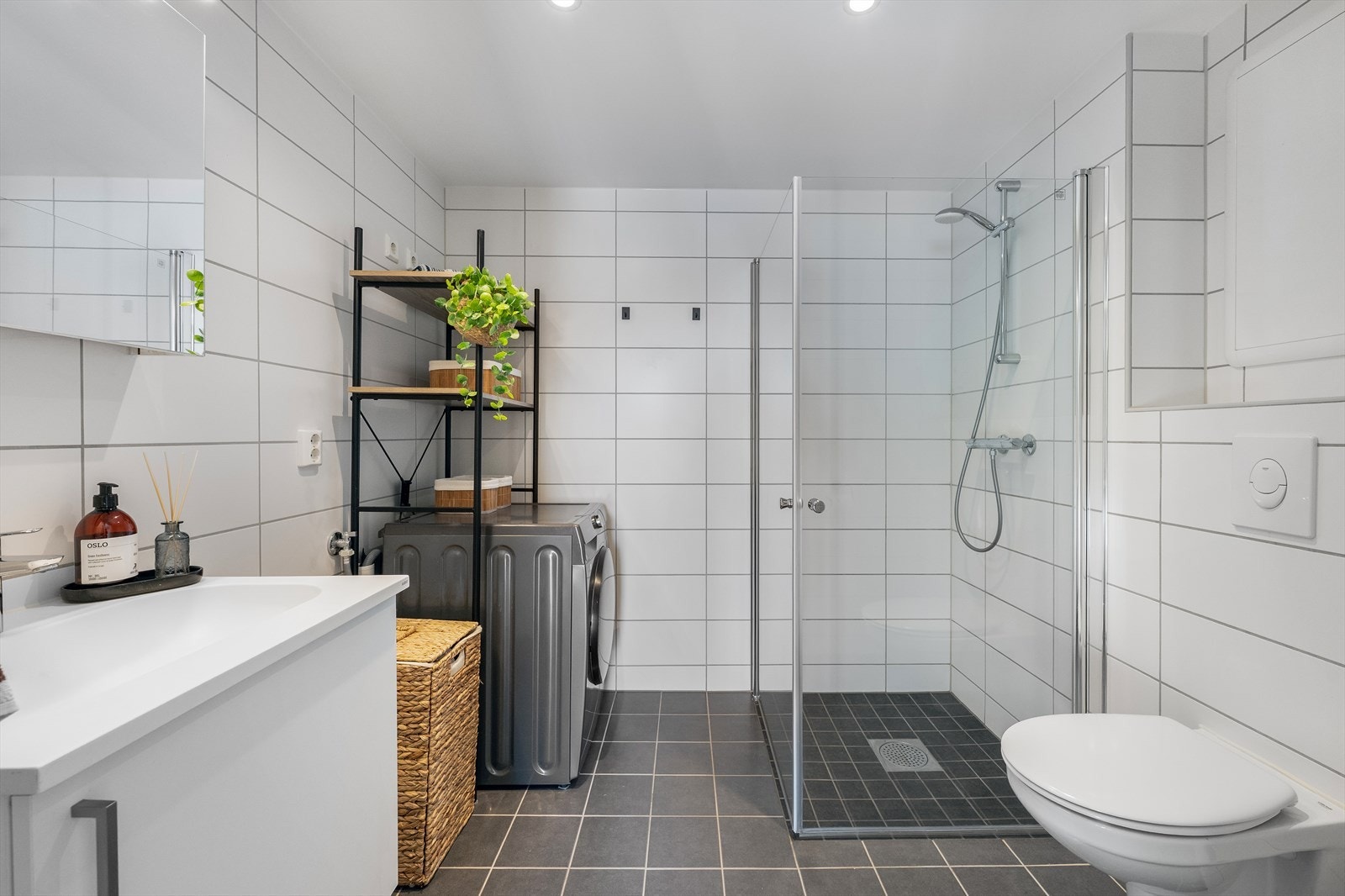 Innredningen består av servant på baderomsinnredning, speilskap, veggmontert toalett, dusjhjørne med innsvingbare glassdører samt opplegg for vaskemaskin,. Galleribilde