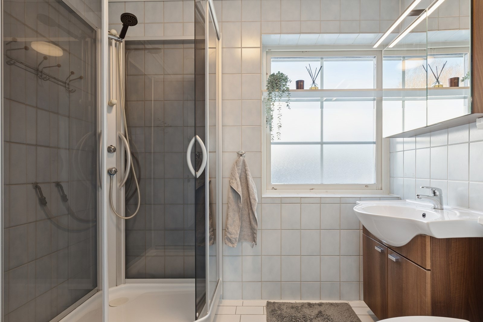 Arealeffektivt og flisbelagt baderom i første etasje med dusj og gulvmontert toalett. Galleribilde