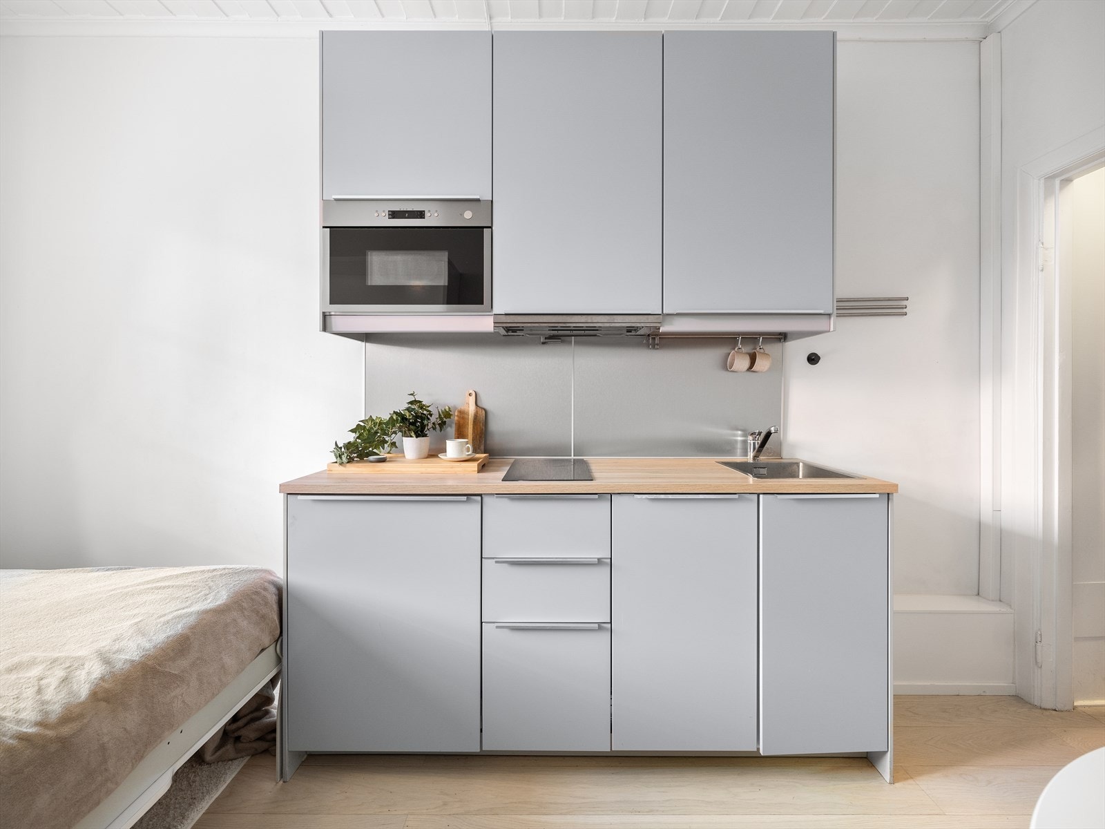 Pent kjøkken med innredning med glatte fronter, benkeplate i laminat og integrerte hvitevarer. Galleribilde