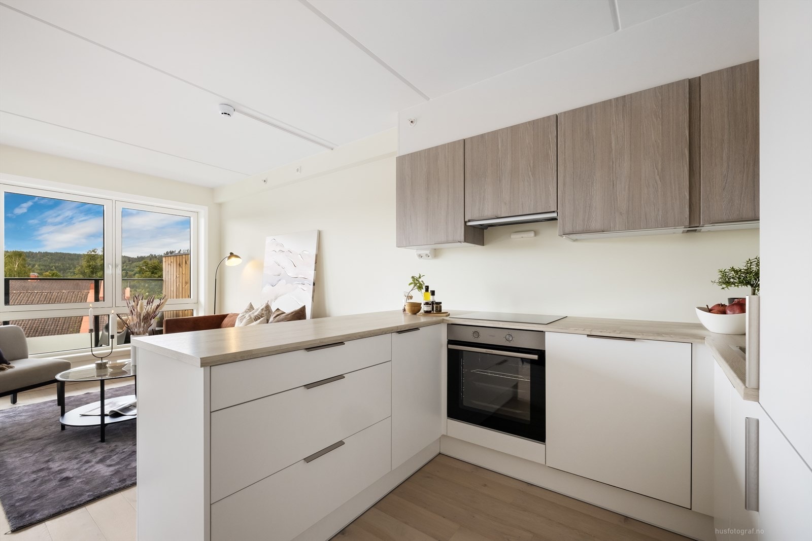 Innredningen på kjøkkenet er i nordisk stil, med hvite, matte høyskap og underskap Galleribilde