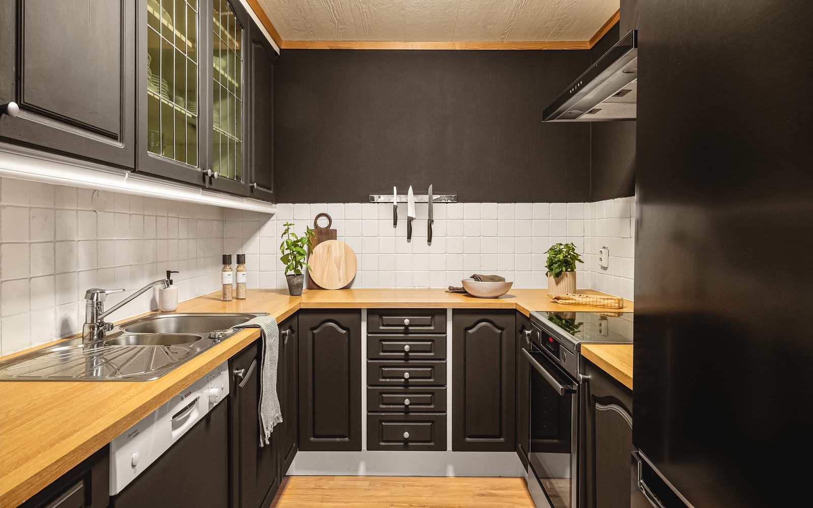 Kjøkkenet måler 5,9 m² og er innredet med takhøy kjøkkeninnredning med profilerte fronter, hvor ett av overskapene har glassfront. Galleribilde