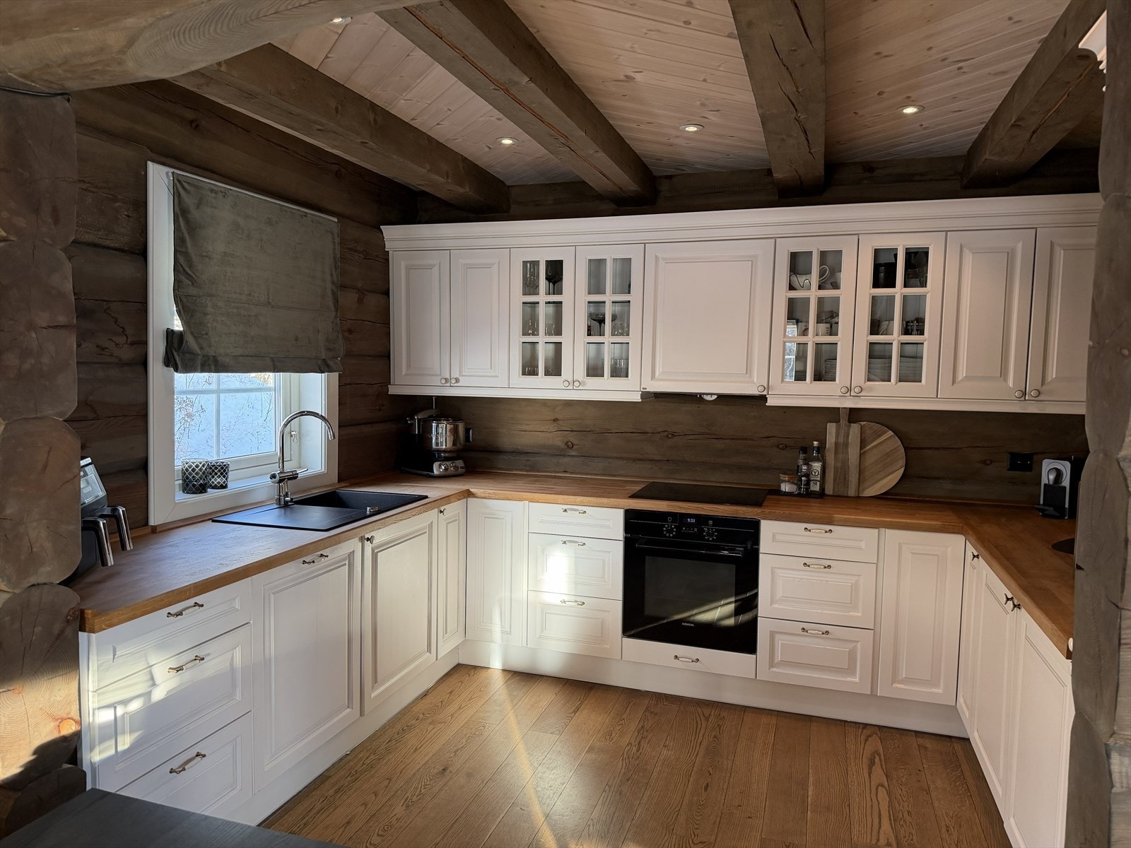 Kjøkken med rikeleg med skap- og benkeplass. Innredning med profilerte, kvite frontar. Integrerte kvitevarer. Galleribilde