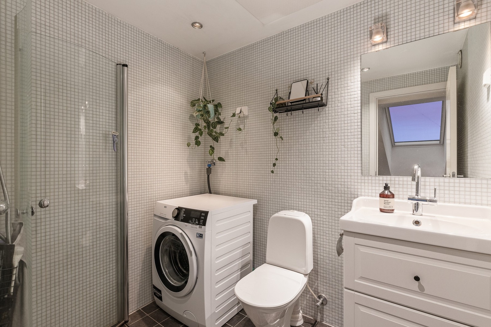 Baderommet er innredet med toalett, servant, toalett, dusj med innfellbare glassvegger og opplegg for vaskemaskin. Galleribilde