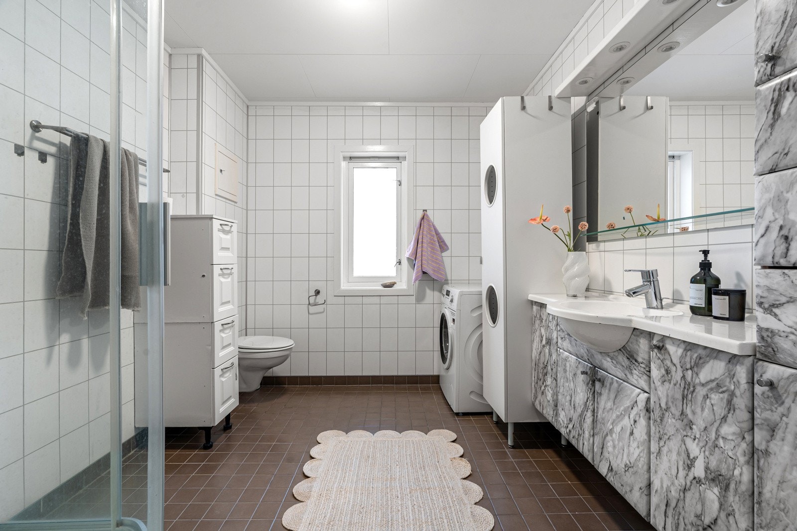 Romslig baderom med dusjkabinett, vegghengt wc og opplegg for vaskemaskin. Galleribilde