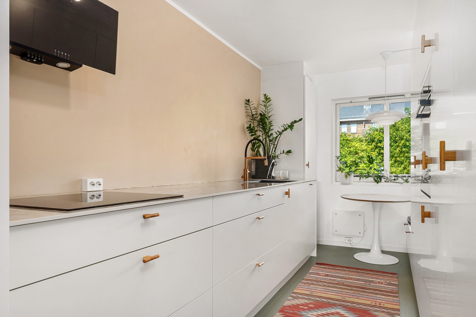 God arbeidsflate på keramisk benkeplate med nedfelt kum og lyse fronter. Innerst i rommet er det etablert en hyggelig sittekrok med utsikt mot nærområdet. Galleribilde