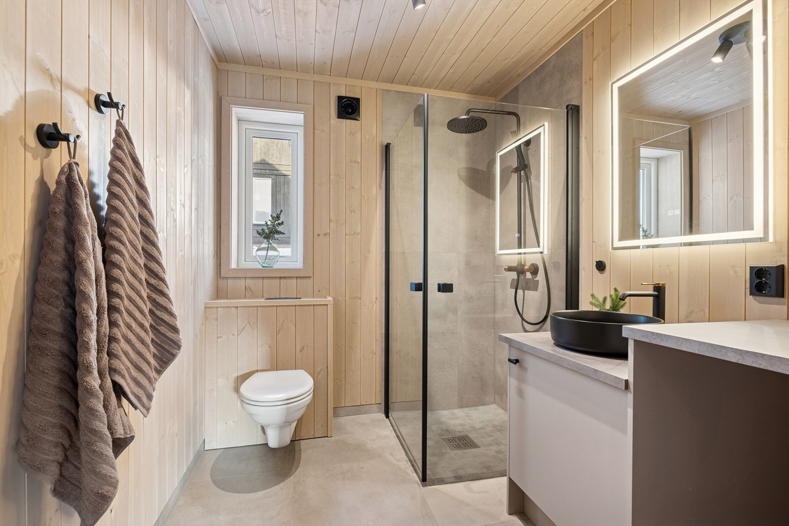 Badet er delikat og moderne, med flislagte gulv og panelte vegger og himling. Galleribilde