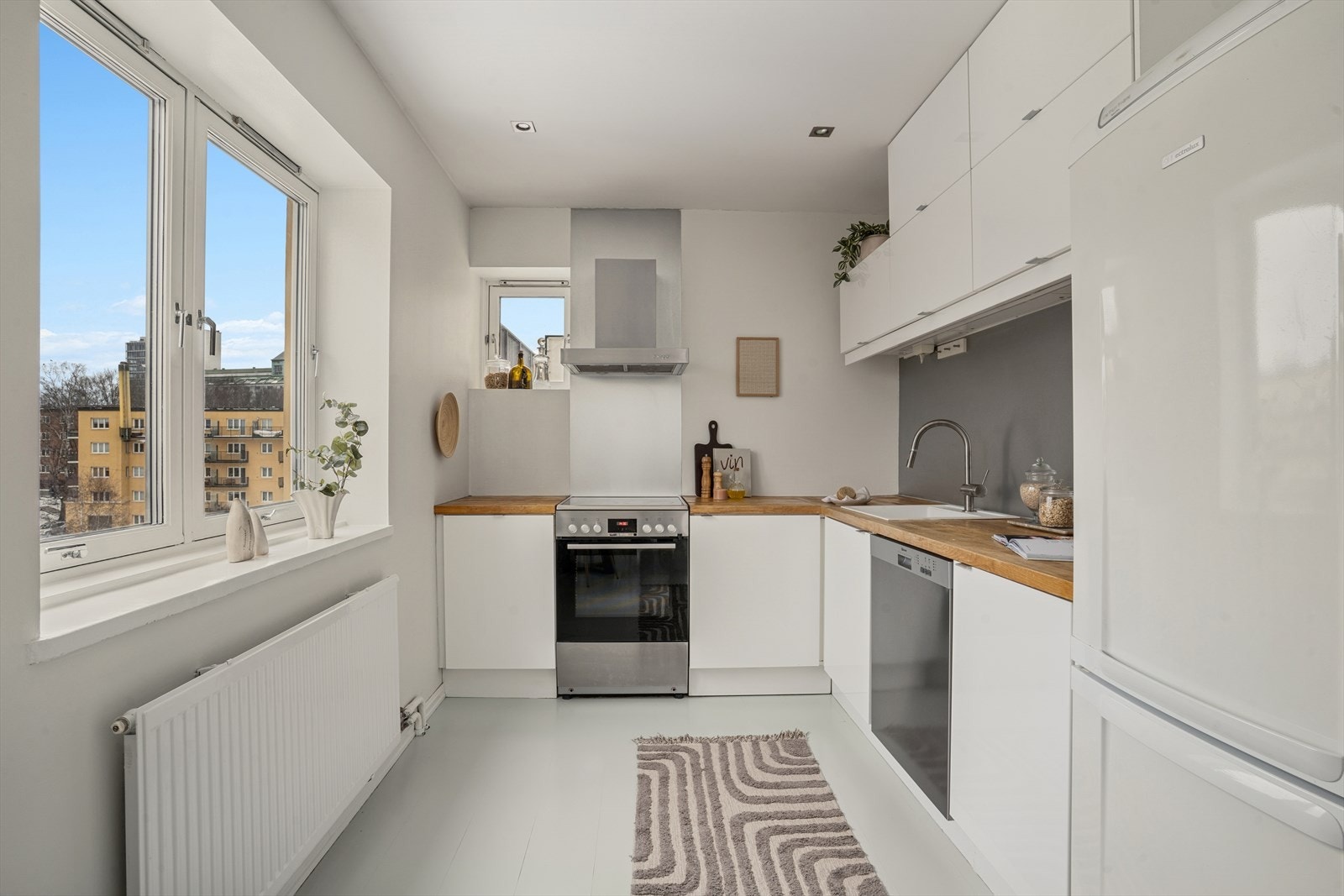 Kjøkkeninnredningen består av glatte hvite fronter og heltre benkeplate. Kjøkkenet ble modernisert med ny servant i kompositt og nytt armatur i 2026. Galleribilde