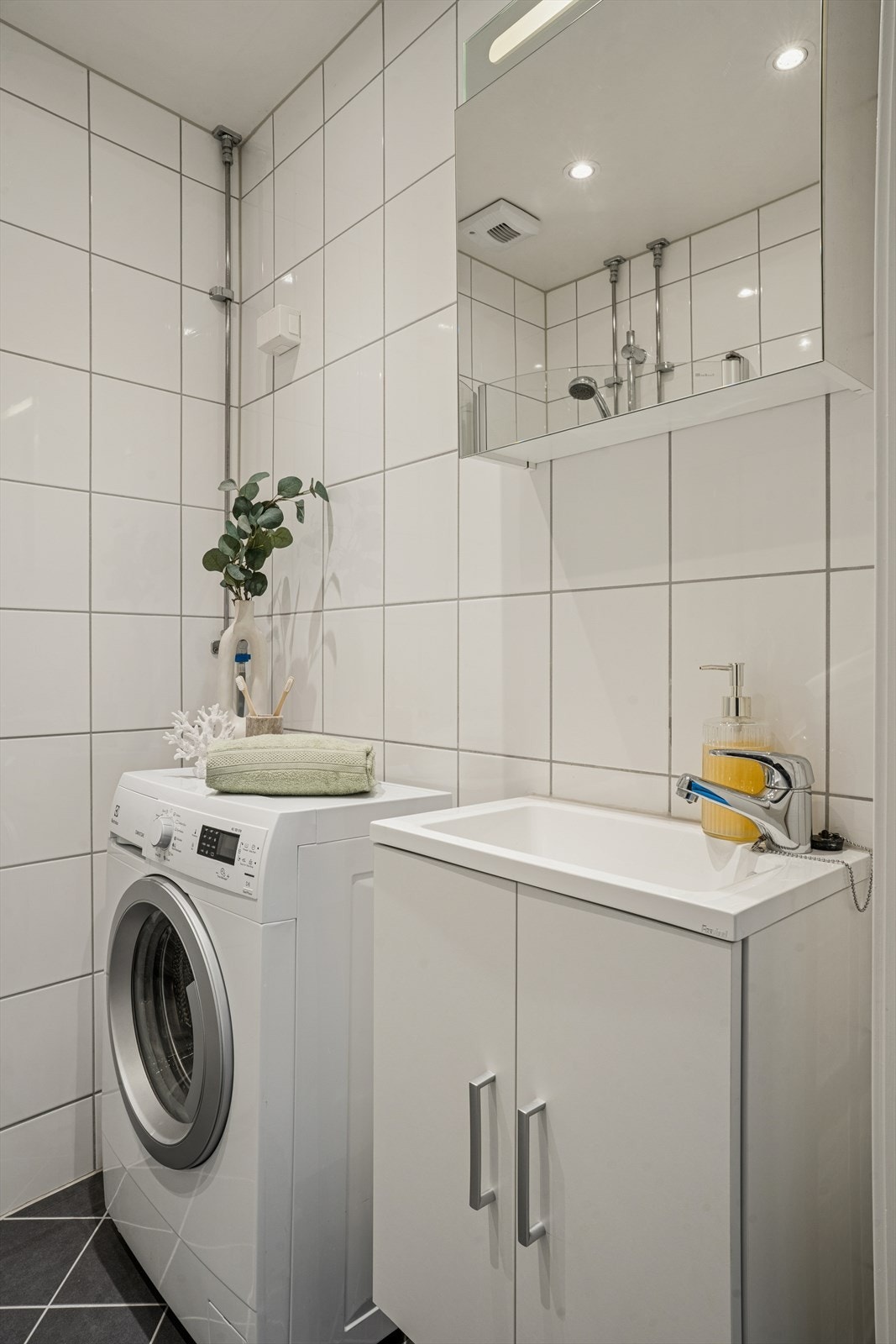 Lyst og moderne baderom med elegante materialvalg. Baderommet har alt du har behov for; dusjhjørne, toalett, servant med underskap og opplegg til vaskemaskin. Galleribilde