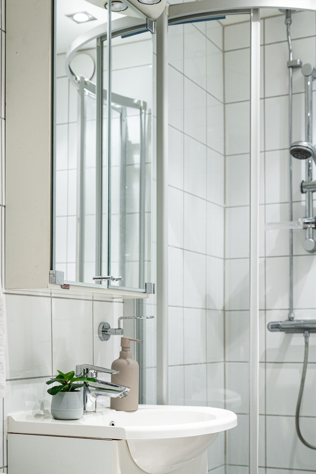 Flislagt bad med speilskap over servanten for praktisk oppbevaring. Galleribilde