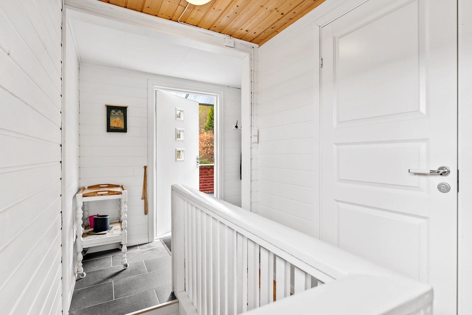 Lys og fin entré med fliser på gulvet, hvitmalt panel på vegger og panel i himlingen. Galleribilde