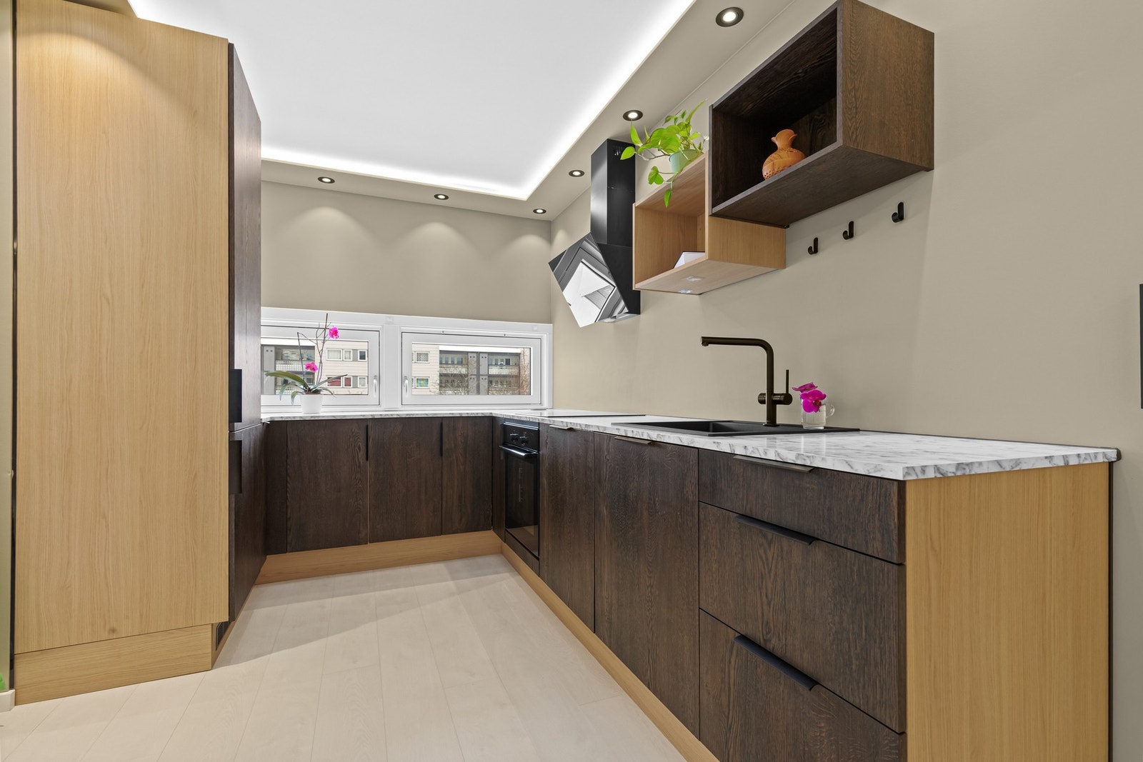 Praktisk kjøkkenløsning med god benkeplass og integrert platetopp, stekeovn og oppvaskmaskin - ventilator med kullfilter over kokesonen. Galleribilde