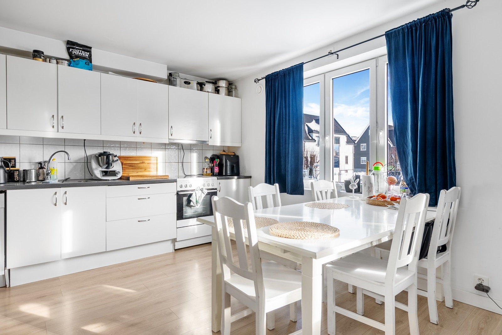 Kjøkkenet har slette lyse fronter og plass for frittstående hvitevarer Galleribilde