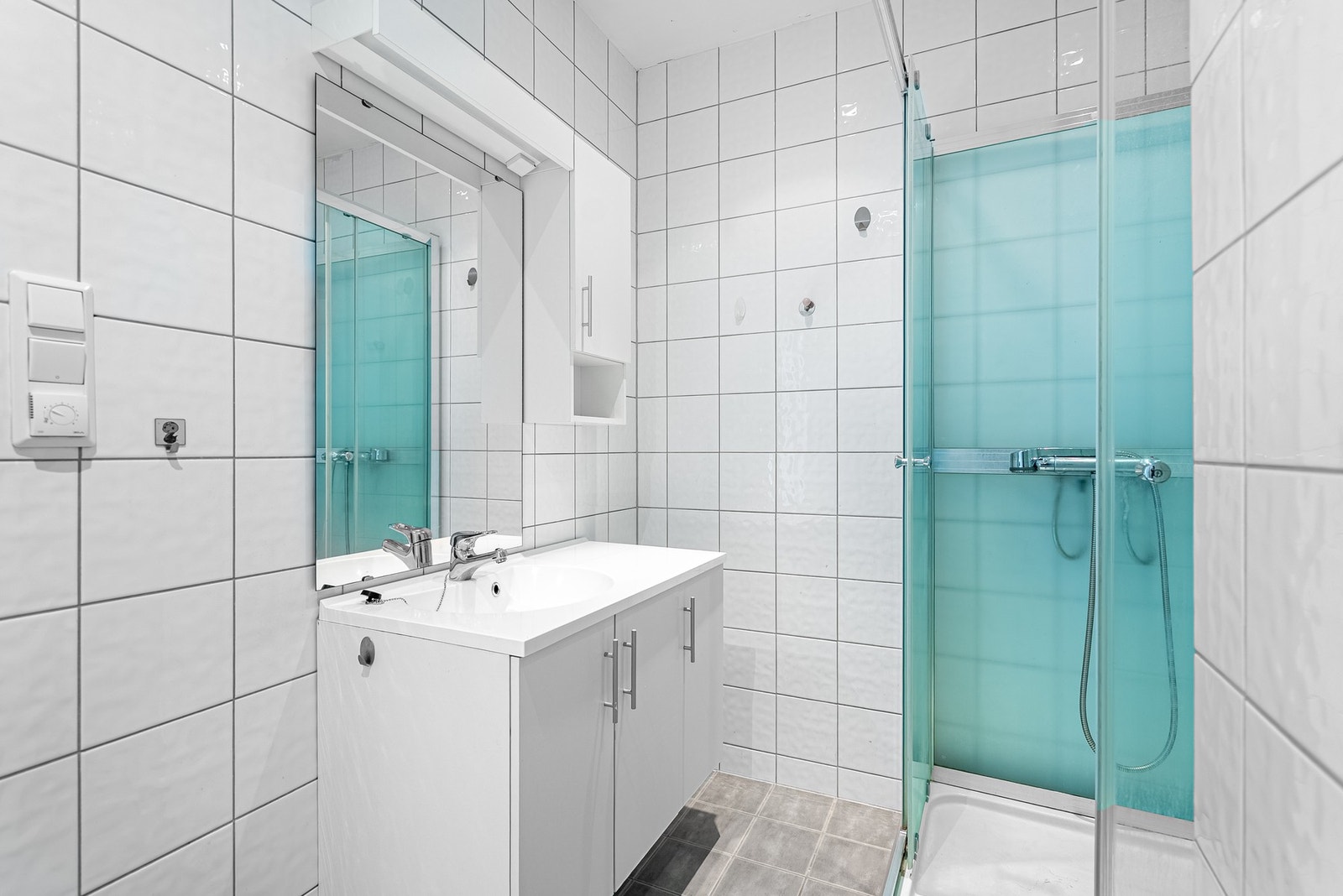 Flislagt bad med varmekabler, servantinnredning med skap, dusjkabinett og toalett - alt du trenger Galleribilde