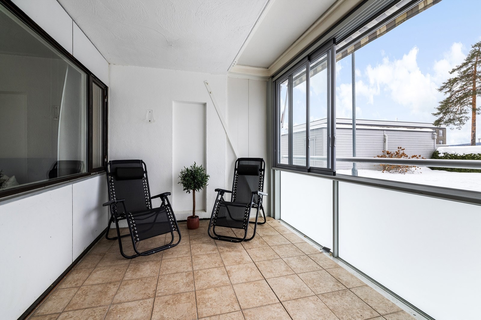 Leiligheten har en innglasset terrasse på bakkeplan med utgang via bred skyvedør fra stue/kjøkken. Galleribilde