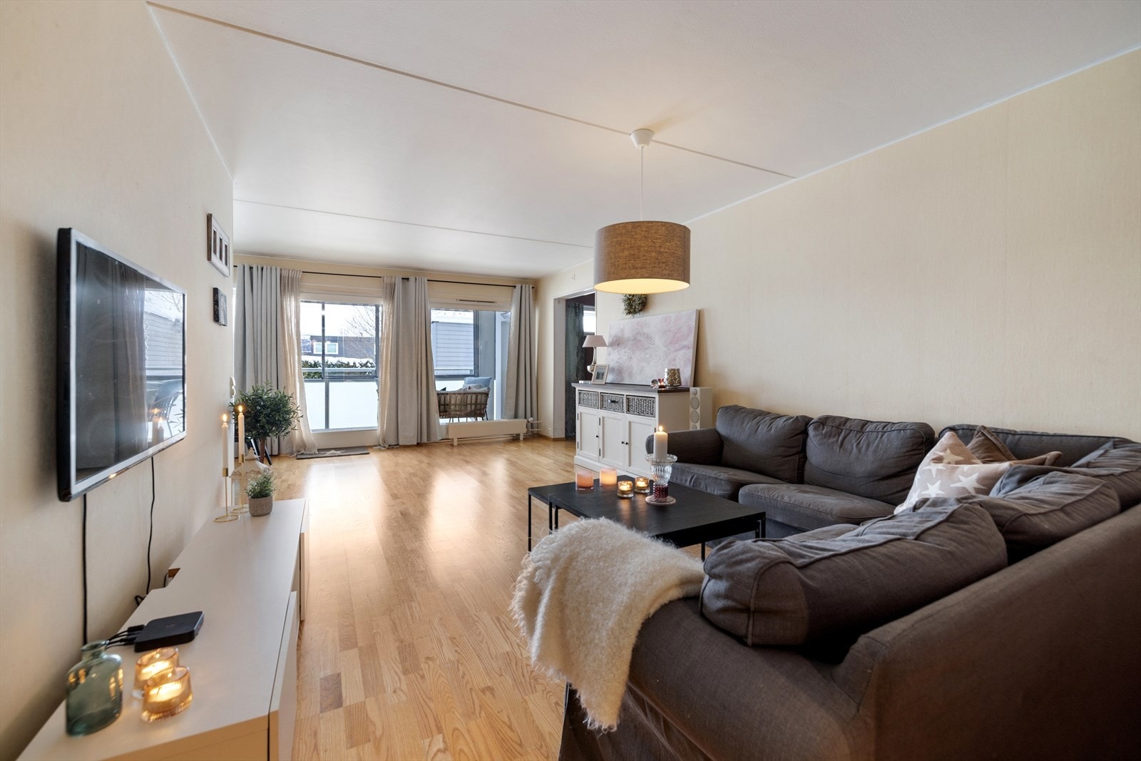 Stue med lyse overflater, parkettgulv og store vinduer som sikrer gode lysforhold. Galleribilde