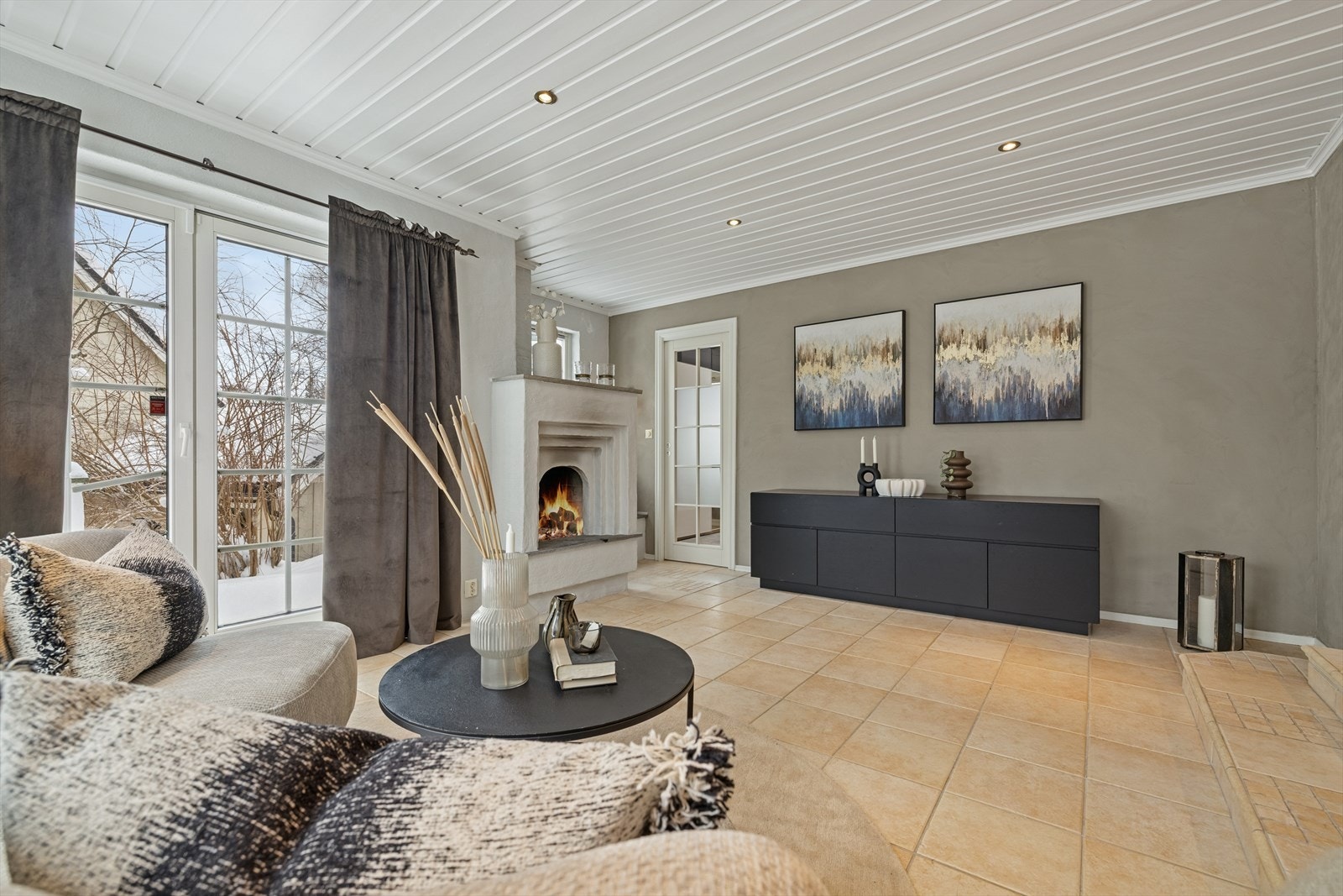 Vinterhagen har fliselagt gulv og en åpen peisovn som skaper en varm og innbydende atmosfære. Galleribilde