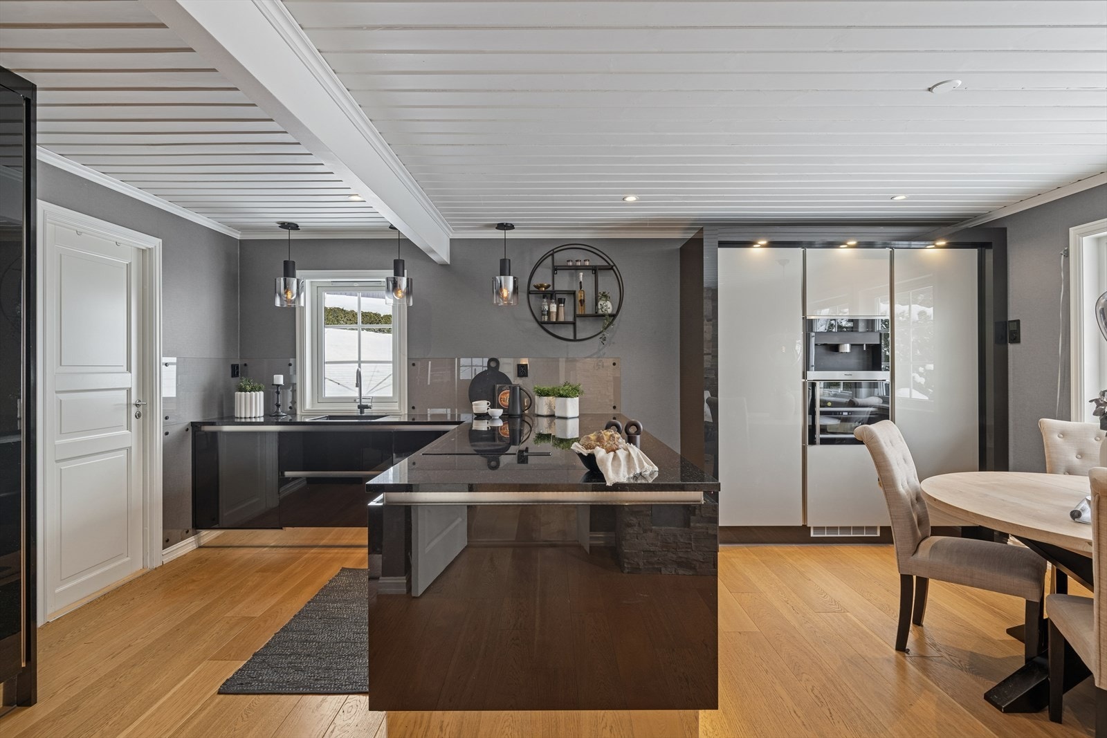 Integrerte hvitevarer som kjølehjørne, varmluftsovn, kombiovn, oppvaskmaskin, bred induksjonstopp, kaffemaskin og vinskap. Galleribilde