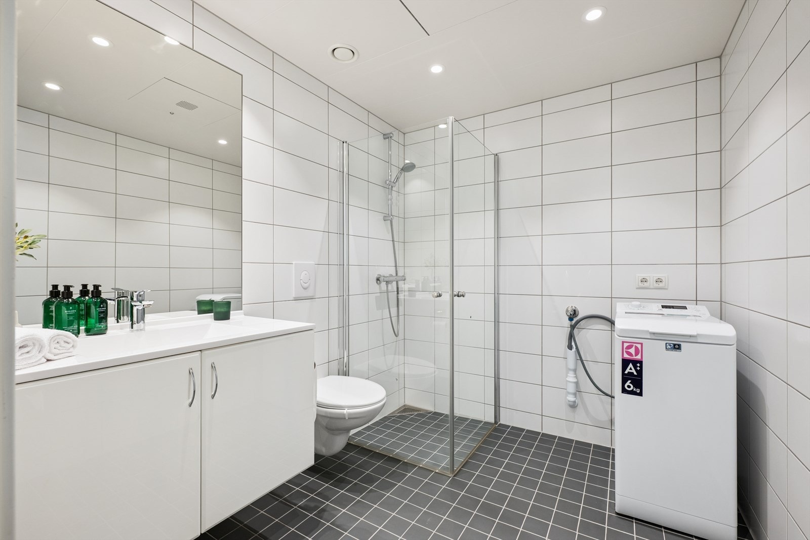 Badet er lyst og attraktivt med flislagte vegger og gulv | Plass til vaskemaskin | Vegghengt toalett. Galleribilde