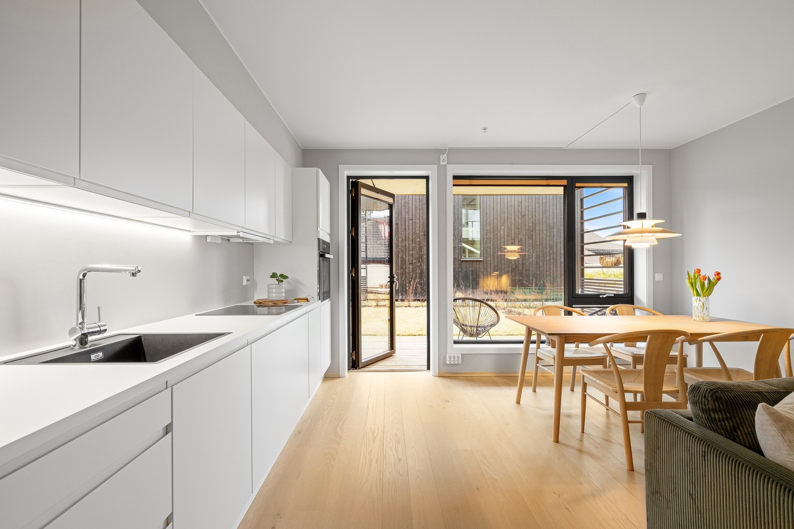 Lyse overflater og en åpen løsning mellom stue og kjøkken som gir en luftig og sosial romfølelse. Galleribilde