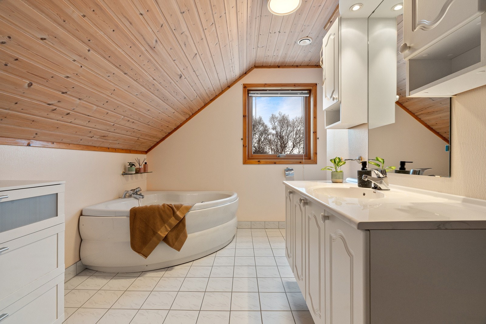 Romslig baderom med hjørnebadekar.