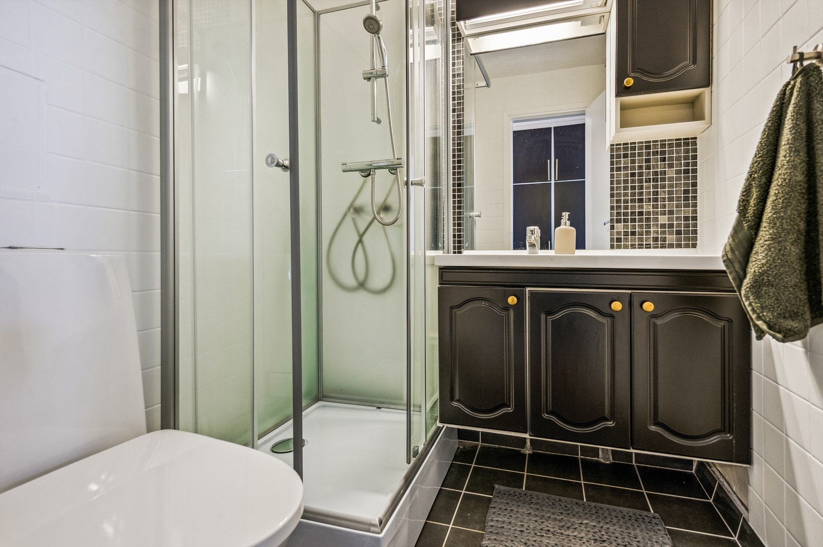 Badet ble oppgradert i 2009 og er helfliset med gulvvarme. Det er innredet med servant med underskap, gulvmontert toalett og dusjkabinett fra 2021. Galleribilde