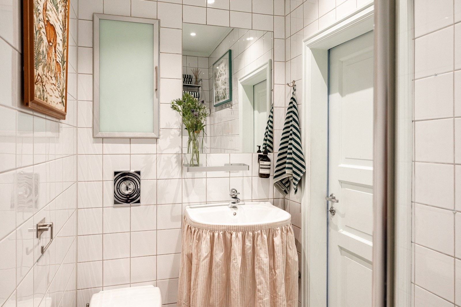 Lyst flislagt bad innredet med servant, veggfestet toalett med skjult sisterne og dusj med en glassvegg. Galleribilde