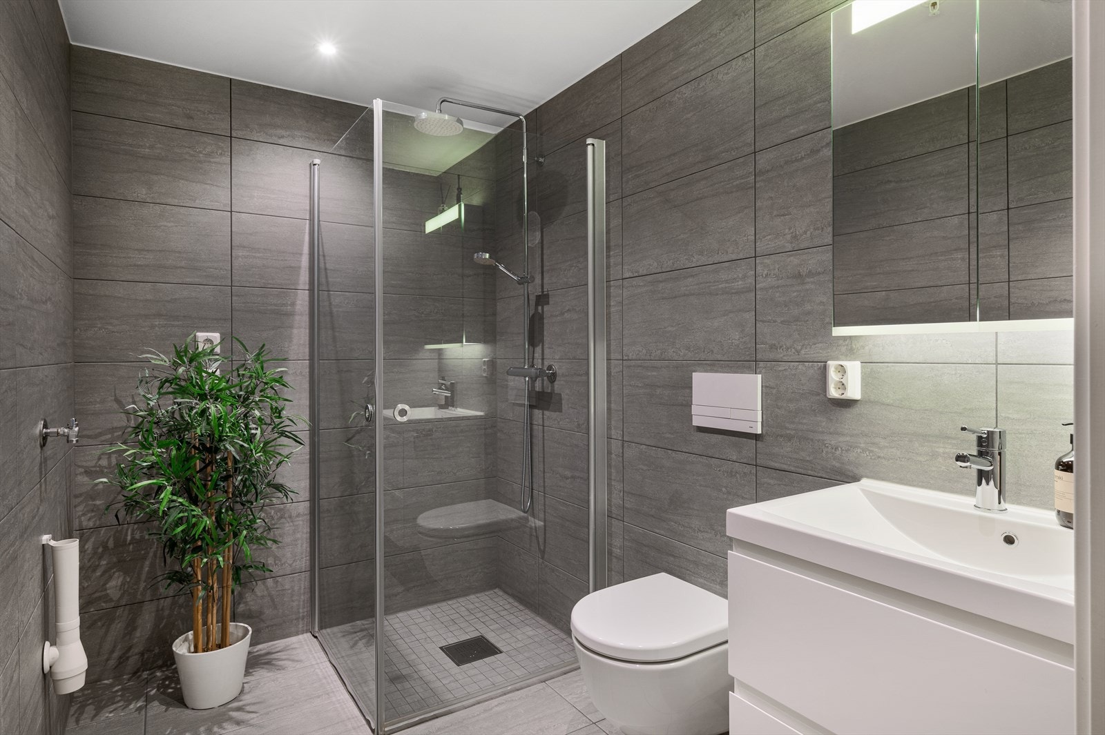 Badet er stilrent, med store fliser, moderne innredning og elektriske varmekabler i gulv. Galleribilde