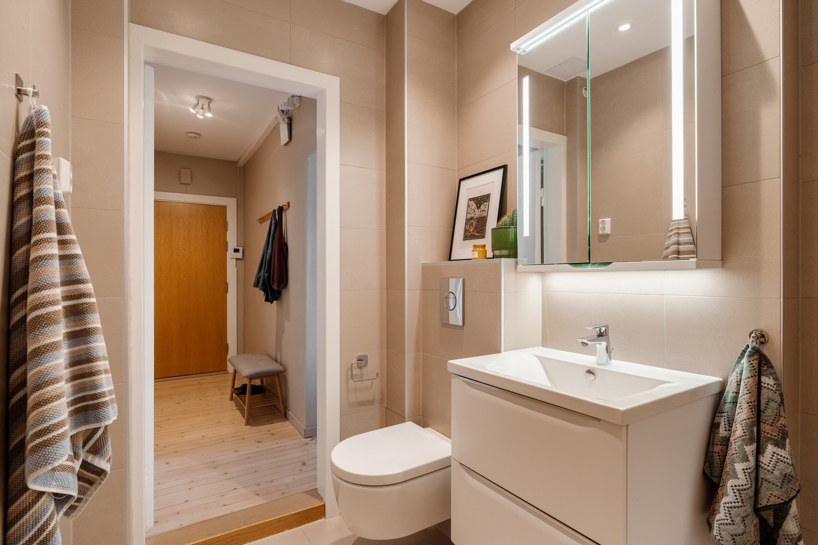 Badet er innredet med vegghengt toalett, dusjnisje, servantseksjon med skuffer og speilskap med integrert belysning. Galleribilde