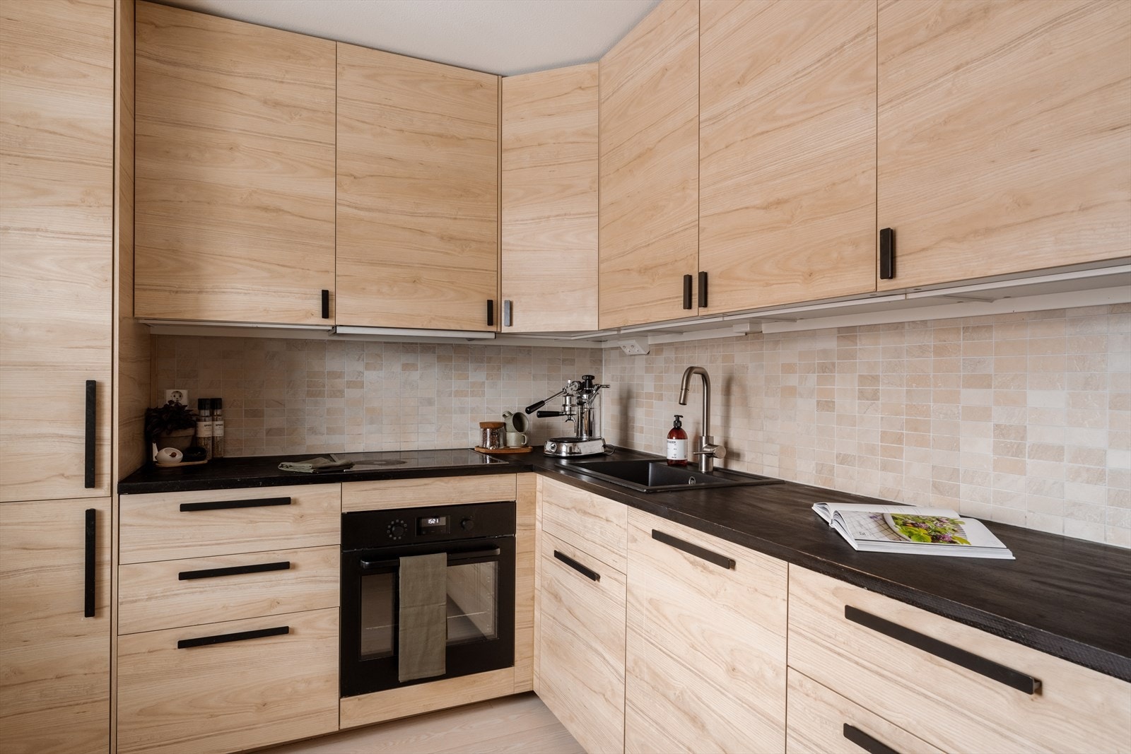 Kjøkkeninnredning med glatte fronter, heltre benkeplate med nedfelt kum. Induksjonstopp, stekeovn, oppvaskmaskin og kjøl/frys er integrert iinnredningen. Galleribilde