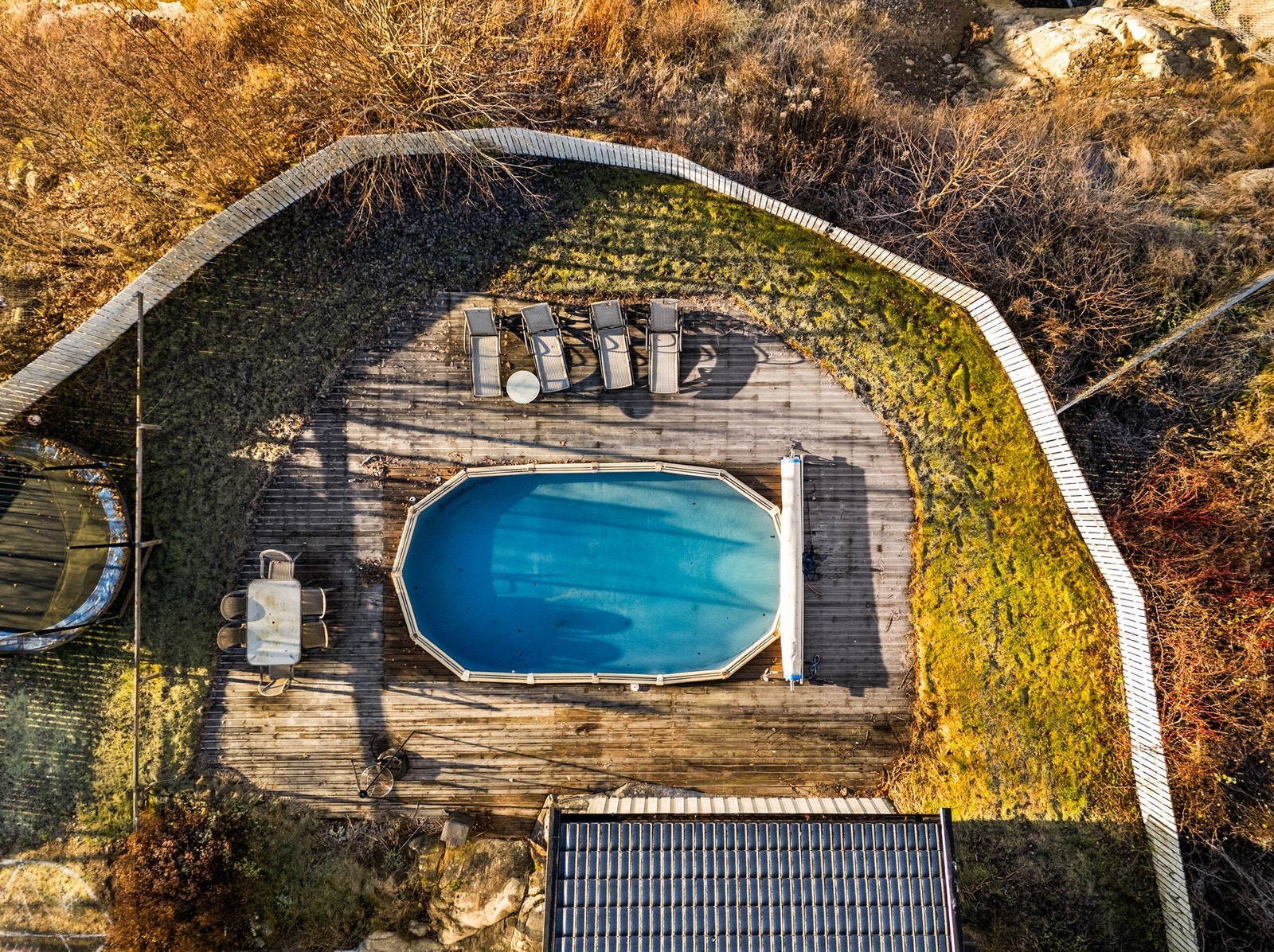 Kul inngjerdet uteplass med platting, basseng og grønne områder. Galleribilde